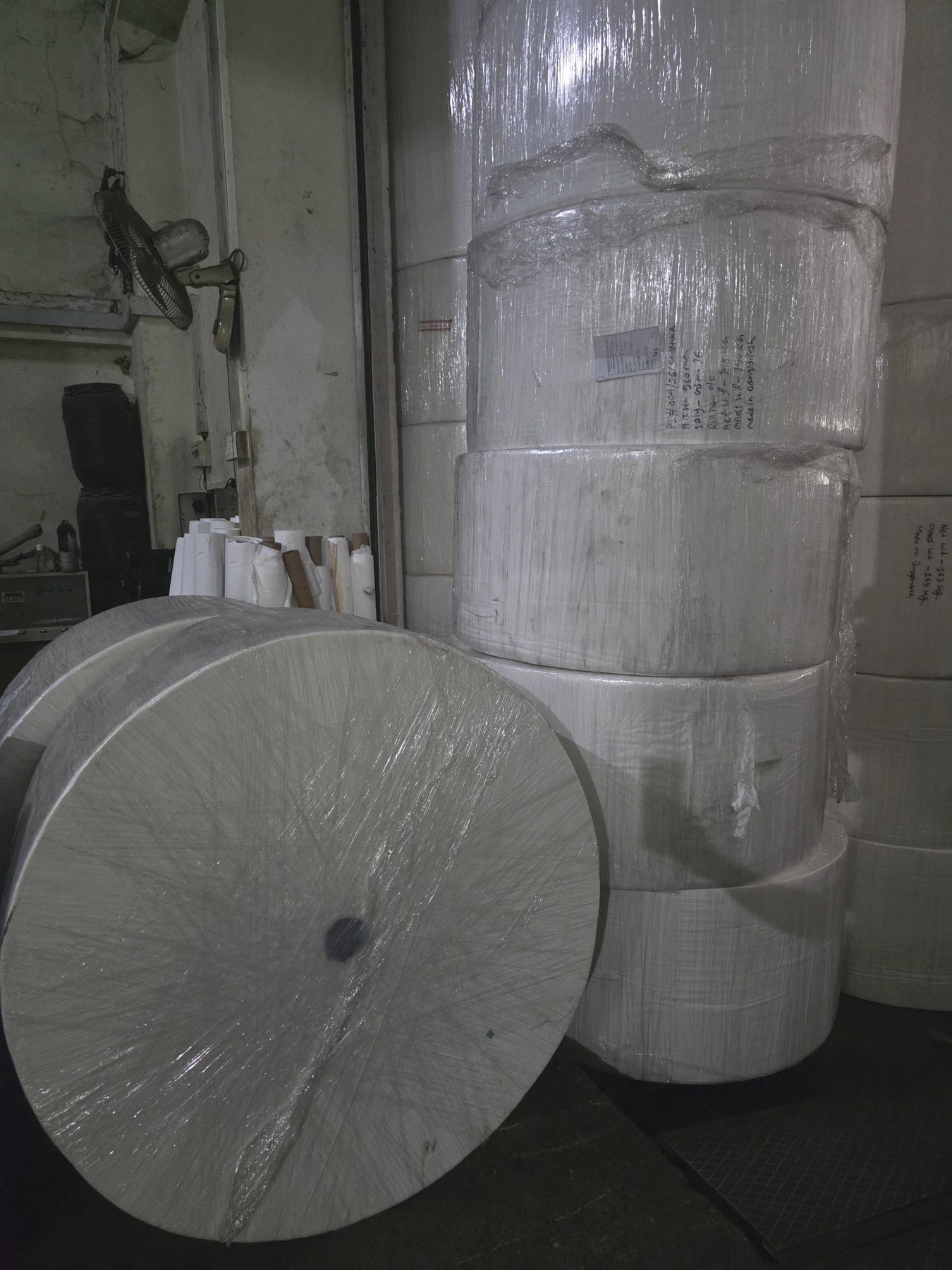 Paper roll end and stacked rolls in warehouse